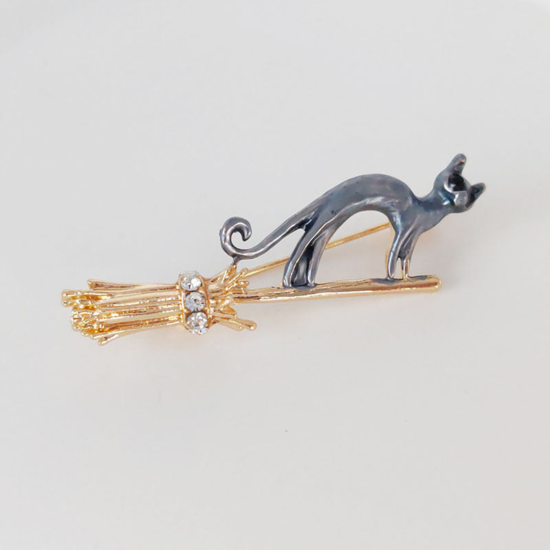 gold cat brooch with broom design